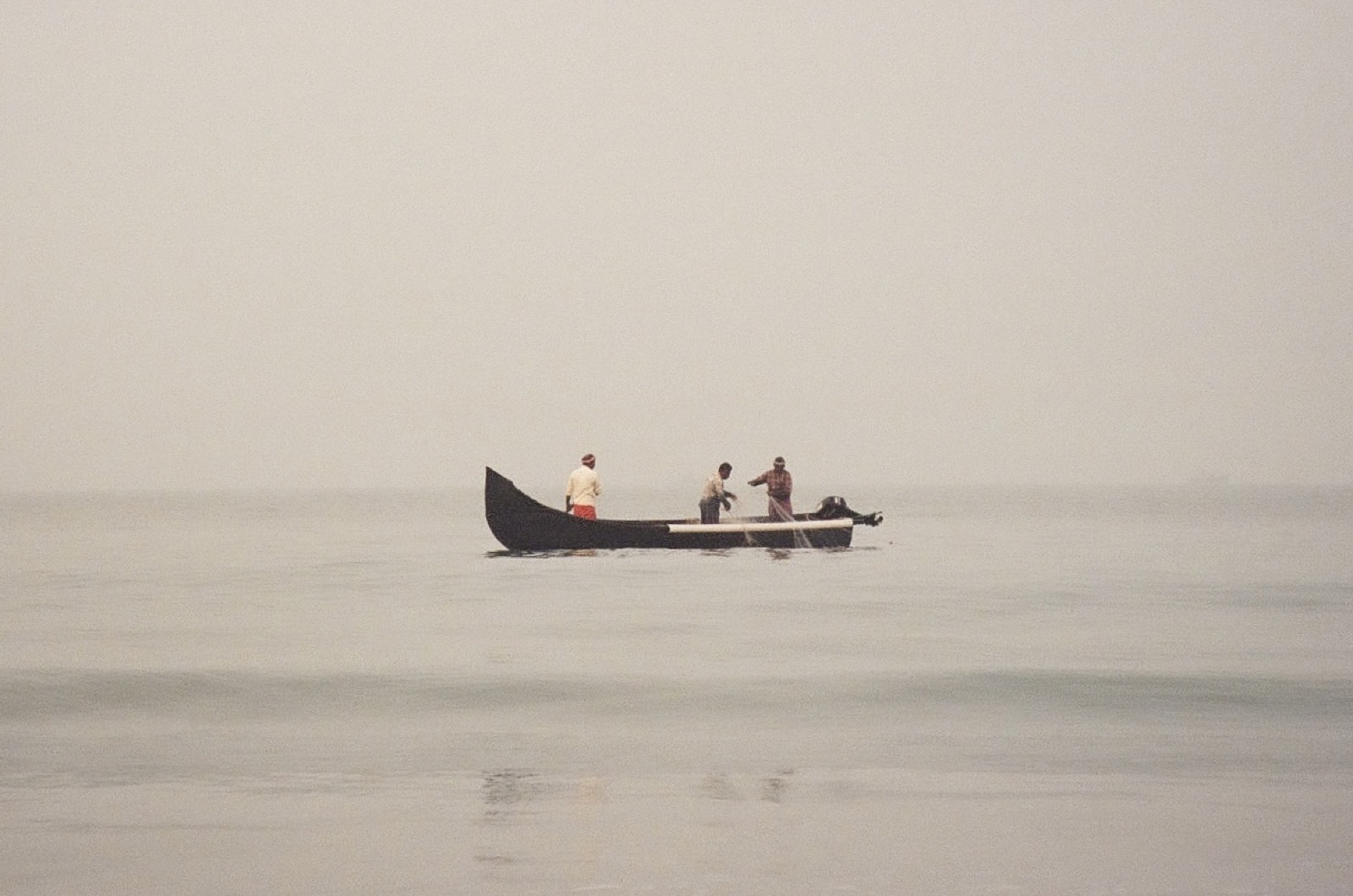 Fishermen in a boat on a still misty sea